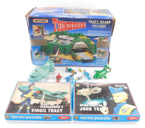 A Matchbox Thunderbirds Tracy Island, boxed, together with a Pilot Thunderbird 2 Virgil Tracy jigsaw puzzle, a Space Monitor John Tracy jigsaw puzzle, Matchbox Thunderbird 2 spaceship figures and a spaceship money box. (a quantity)