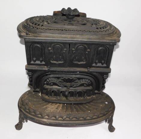 A Victorian cast iron kitchen range by The Columbian Stove Works., of oval form, with a pierced shell and scroll decorated cover, cast sliding doors and drawer, raised on a shaped oval base, on cabriole legs, 59cm high, 53cm wide, 57cm deep. Auctioneer No