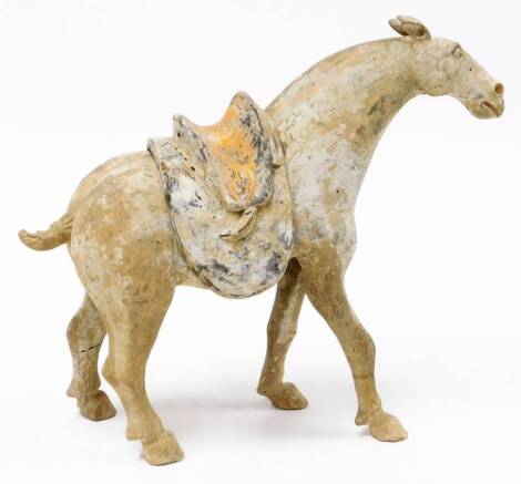 A unglazed Tang Dynasty painted pottery figure of a horse, one foot raised, with detachable saddle, 35cm high. Note: This lot comes with a thermoluminescence analysis report from Oxford Authentication.