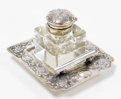 A Chinese silver ink stand, the cut crystal well having a repoussé decorated cover, the square stepped base with floral decoration pen rest and makers mark YOKSANG to base, 11cm square.