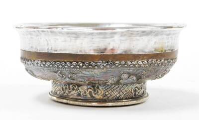 A 19thC Tibetan silver and turned birchwood cup, with a plain insert and fold over rim, the base highly decorated with a band with eight immortal emblems and an entwined dragon with flaming pearl amidst a sea of clouds, 13cm diameter.