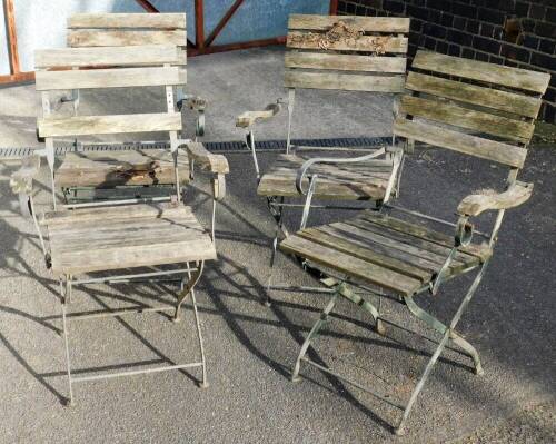 Four wrought iron folding garden chairs, with wooden slatted seats and backs.