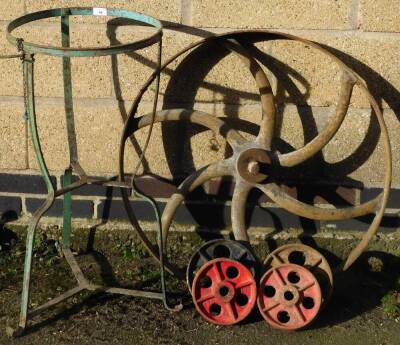 A cast iron fly wheel, 76cm diameter., other small wagon wheels and a wrought iron bagging stand.