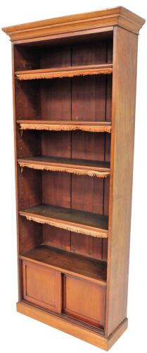 A Victorian mahogany open bookcase, with moulded cornice and adjustable shelves with tassels over a sliding door base on plinth, 209cm high, 84cm wide, 30cm deep.