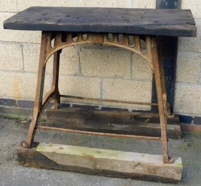 A Victorian cast iron table base, with wooden top and trestle base, 96cm high overall, 110cm wide, 46cm deep.