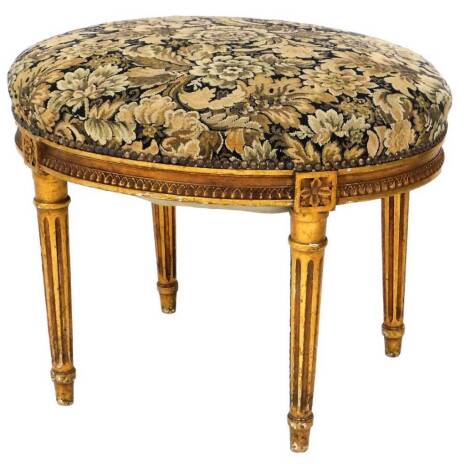 A 19thC oval giltwood stool, with overstuffed and sprung tapestry seat, and reeded taper legs, 50cm high, 64cm wide, 50cm deep.