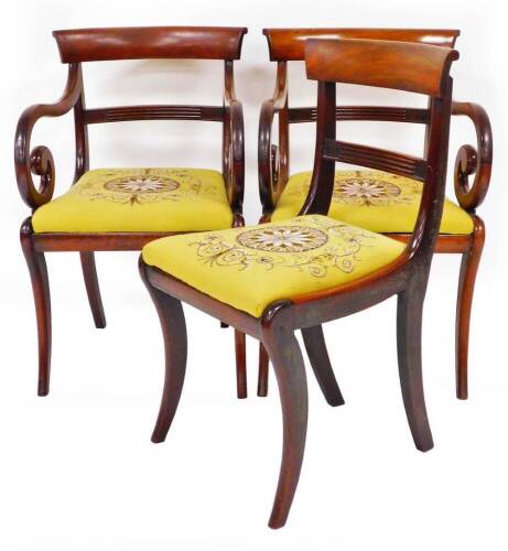 Two 19thC mahogany carver chairs, each with shaped cresting rails and horizontal splats, drop in seats in later floral material on yellow ground and sabre front and back legs, 85cm high, and a further dining chair similar. (3)