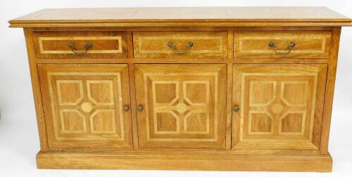 A supremely weighted 20thC walnut sideboard, in the manner of David Linley, with parquetry inlaid banded top, above three drawers with brass handles and two cupboard doors, on a plinth base, 90cm high, 182cm wide, 50cm deep.