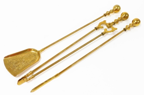 A set of brass fire implements, comprising poker, tongs and shovel, each with bulbous end, approximately 70cm high.