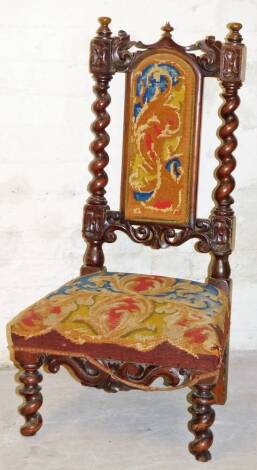 A 19thC Continental nursing chair, the arched back and shaped seat upholstered in a petit point style floral design in various colours , with compressed finials, barley twist supports and similar front legs, with a heavily carved apron, probably shortened