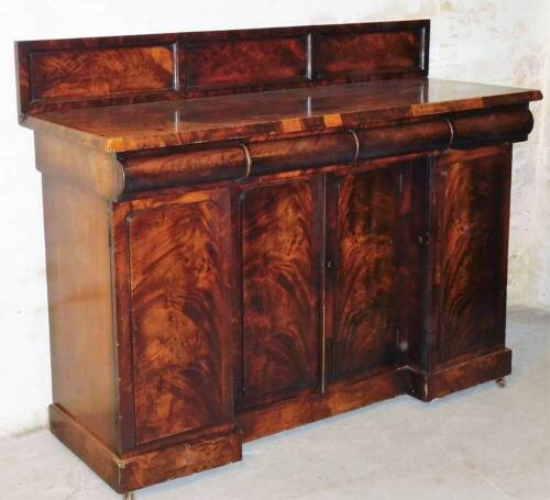 A Victorian mahogany inverted break front sideboard, the plain panelled back raised above a cushion drawer and double cupboards, flanked by further cupboards plnth base, 120cm high, 150cm wide, 56cm deep.