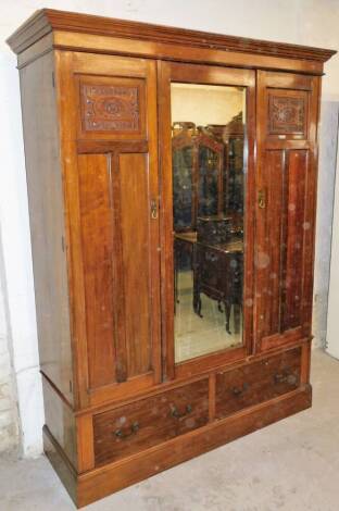 A late Victorian walnut stained wardrobe, the central bevel glass mirror flanked by two doors, with two frieze drawers beneath on a plinth base, 210cm high, 160cm wide, 58cm deep.