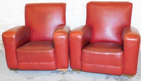 A pair of mid 20thC vintage armchairs, each in red leatherette with fixed cushions, on castors, probably 1950's, 82cm high, 73cm wide, 82cm deep. (2) The upholstery in this lot does not comply with the 1988 (Fire & Fire Furnishing) Regulations, unless sol