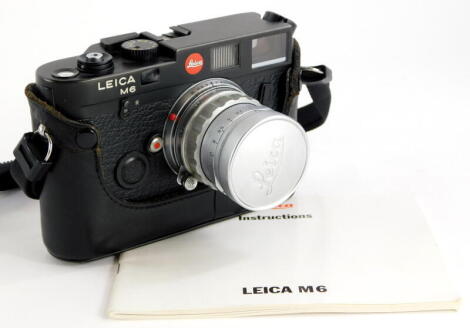 A black Leica M6 camera, with a Leitz 5cm f2 Summicron lens, number 1581384, and a half leather case.