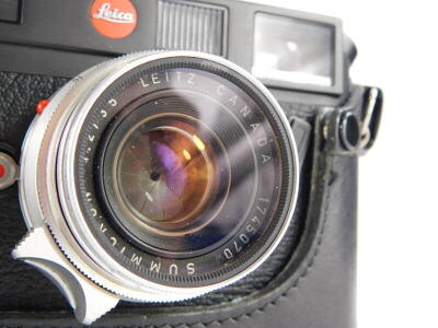 A black Leica M6 camera, with a Leitz 35mm f wide angle Summicron lens, number 1745070, in a leather case. - 2