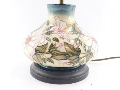 A Moorcroft pottery table lamp decorated in a floral pattern, of baluster form against a cream to blue ground, 27cm high.