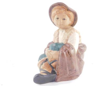 A Nadal matt pottery figure of a boy, modelled seated, printed marks, 22.5cm high.