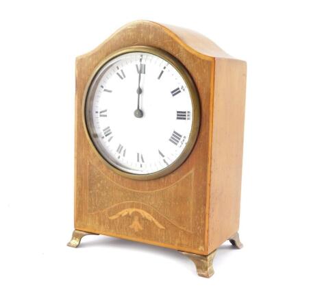 An Edwardian mahogany and inlaid mantel clock, enamel dial bearing Roman numerals, clock work movement, the case of domed form, raised on brass bracket feet, 18cm high, 12cm wide.