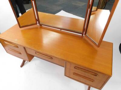 A G plan teak dressing table, with a tryptic mirror back, over a central fitted jewellery drawer, flanked by four further drawers, raised on X shaped end supports united by a single stretcher, 131.5cm high, 137cm wide, 46cm deep. - 2