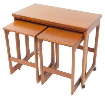 An A H Mackintosh & Company Ltd teak trolley, with a fold over top, enclosing two smaller tables, raised on curved supports, on casters, largest table 63cm high, 76cm wide, 40cm deep.