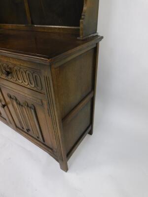 An oak dresser, the out swept pediment above a two shelf plate rack, over two frieze drawers above linenfold panelled doors, raised on channel square legs, 182.5cm high, 127 cm wide, 38cm deep. - 3