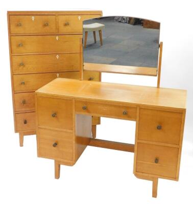 A mid century Georgian style light oak chest, of two short over five long drawers, raised on tapering square legs, 128cm high, 84cm wide, 45cm deep, together with a dressing table, the domed swing framed mirror over one long flanked by four deep drawers,