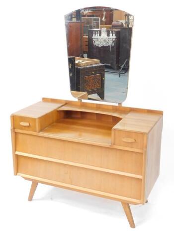 A 1950's vintage walnut dressing chest, possibly by Alfred Cox, the shield shaped mirror above a shallow curved shelf, flanked by two short drawers over two long drawers, raised on out swept legs, 144.5cm high, 99cm wide, 44cm deep.