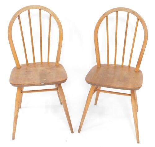 A pair of Ercol mid century ash and elm Windsor kitchen chairs, with solid seats, raised on turned legs united by an H frame stretcher.