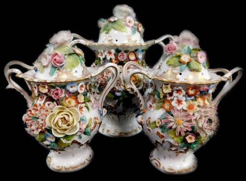 A garniture of three Derby style pot pourri vases, with rose covers and floral encrusted bodies, 22cm high, and 17cm high.