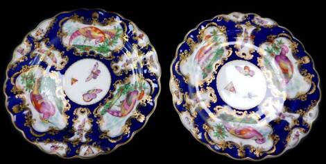 A pair of first period Worcester style porcelain plates, possibly Booths, painted with reserves of exotic birds and butterflies against a scale cobalt blue ground, 22cm diameter.