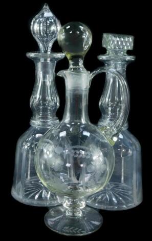 A pair of Victorian cut glass mallet shaped decanters, with one stopper, a further pressed glass matched stopper, and a cut glass claret jug and stopper, engraved with repeating flowers heads and leaves.