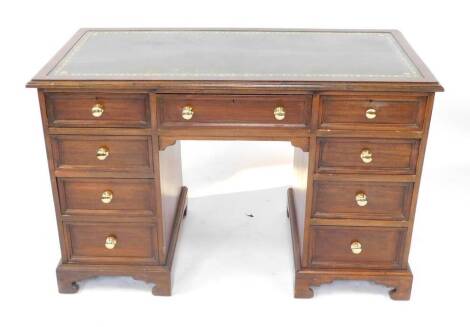 An oak twin pedestal desk, with tooled green leather top, over one long and eight short drawers raised on ogee bracket feet, 77cm high, 120cm wide, 57cm deep.