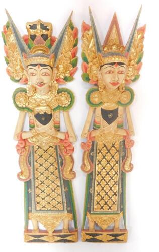 A pair of Balinese wooden carvings of male and female deities, modelled in standing pose, 97cm high.