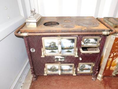 A Continental early 20thC cast iron and enamel kitchen range, the doors and sides decorated with panels of lakeside views, raised on lion's paw feet, 79cm high, 103cm wide, 62cm deep.