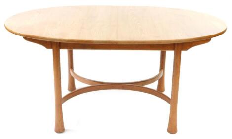 An Ercol light elm draw leaf dining table, the oval top raised on cylindrical club legs united by an X framed stretcher, 73.5cm high, 160cm wide, 211cm extended, 105cm deep.