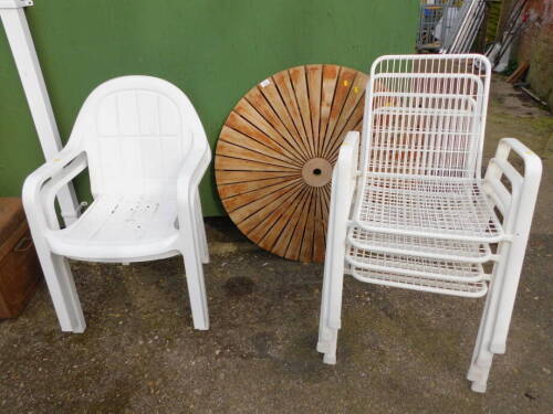 Three plus two stacking white garden chairs and a circular folding table.