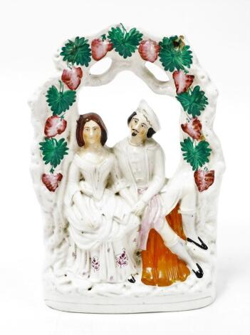 An early 19thC Staffordshire flat back figure group, of male and female seated, with strawberry leaf arch, 35cm high.