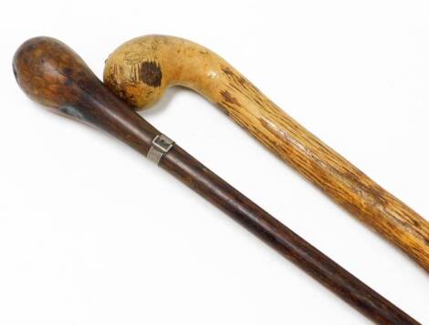 Two walking canes, comprising a mahogany swagger stick with silver plated buckle collar bearing the initials HGW, with a brass tap end, 84cm long, and another elm example with turned handle on rubber end, 89cm long. (2)