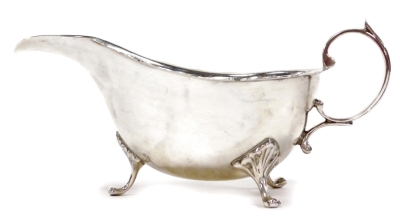 A George V silver sauce boat, with a shaped edge, scroll handle and shaped legs, headed by leaf casting, Birmingham 1920, 4½ oz.