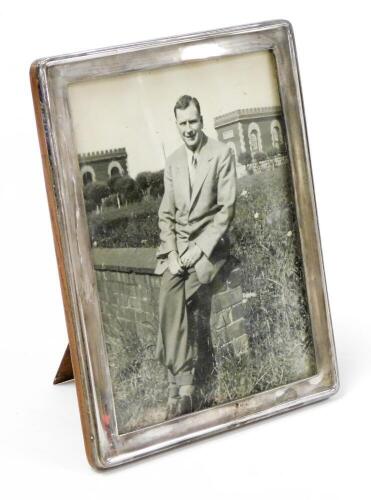 George V silver photograph frame, rectangular shaped, with silvered border on a formed back, with black and white photograph of a gentleman, Birmingham 1931, 23.5cm high x 18.5cm wide.