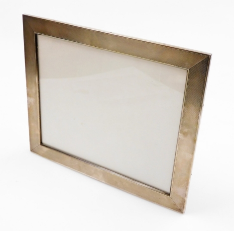 A large late 19thC easel backed photograph frame, with engine turned decoration throughout, with wooden backing, the border white metal, stamped 925, 36.5cm x 30.5cm.