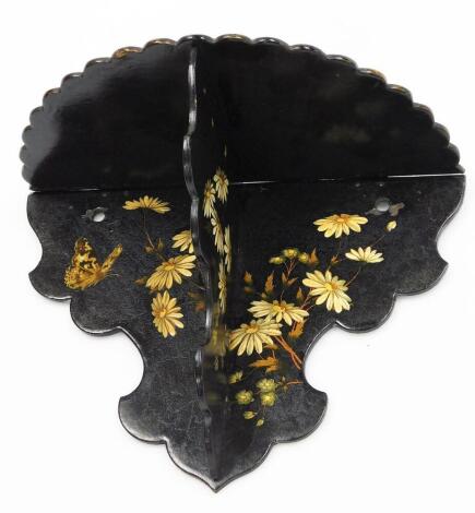 A late Victorian black lacquered wall shelf, with applied floral decoration and butterflies, with pie crust borders, 19cm high, 26cm wide.