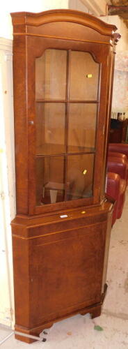 A walnut corner cabinet, with shaped cornice, above six sectional astragal glazed door, with cupboard base, 182cm high.