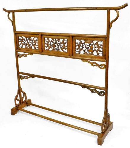 A Chinese elm robe rack with pierced fretwork panels depicting bats, gourds, musical instruments, possibly 19thC, 164cm high, 181cm wide.