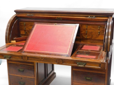 A late Victorian walnut cylinder desk, with a moulded top and a triple panelled fall, enclosing a fitted interior with red leather insets, pigeon holes and drawers, each with teardrop handles above six drawers, each with engraved brass drop handles, on a - 3