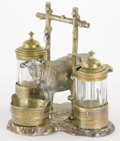 A Victorian silver plate and glass novelty cruet, cast with a cow and a stylised branch handle, the shaped platform applied with three milk buckets for salt, pepper and mustard, lozenge marks and makers mark for T.W., 14cm wide.