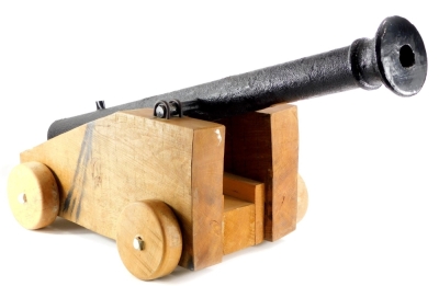 A cast iron replica small canon, on oak trunnion, with solid wheels, the canon 113cm long.