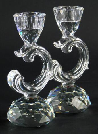 A pair of Swarovski Crystal candlesticks, each with scroll shaped support and faceted tapering base, 13cm high.