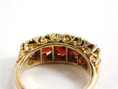 A 9ct gold garnet set gypsy ring, with five garnets and tiny diamond set shoulders, in a raised claw setting, with scroll design shoulders, ring size O, 4.9g all in, boxed. - 2