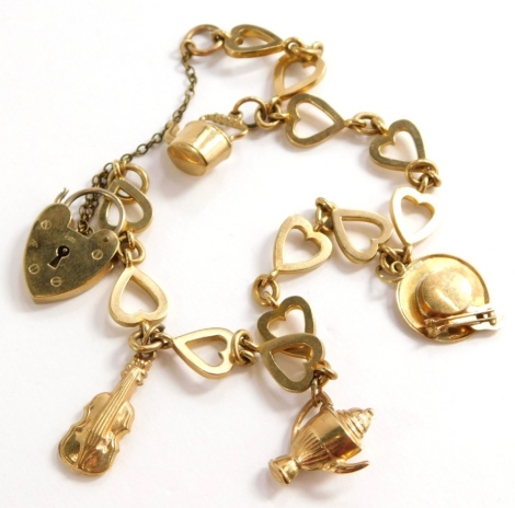 A charm bracelet, with various heart shaped links, each stamped 9c, with a heart shaped padlock and various charms, to include violin, teapot, coffee pot and hat with mandolin, joined with a later possibly gold plated safety chain, approx 26cm long, 15.3g